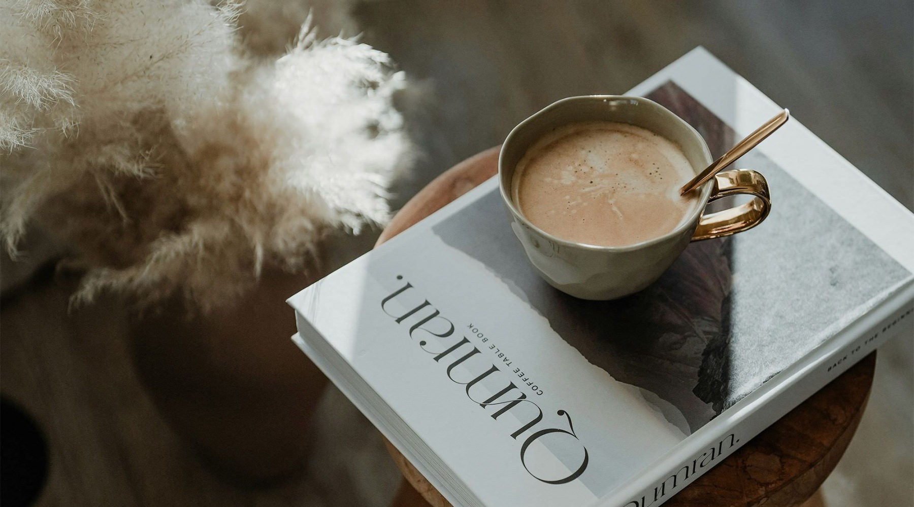 a cup of coffee on a book on a stool in a living room